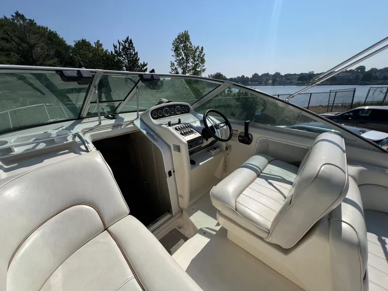 Slide: The Image of 1997 Sea Ray 270 Sundancer boat interior with white seating at marina. - 8