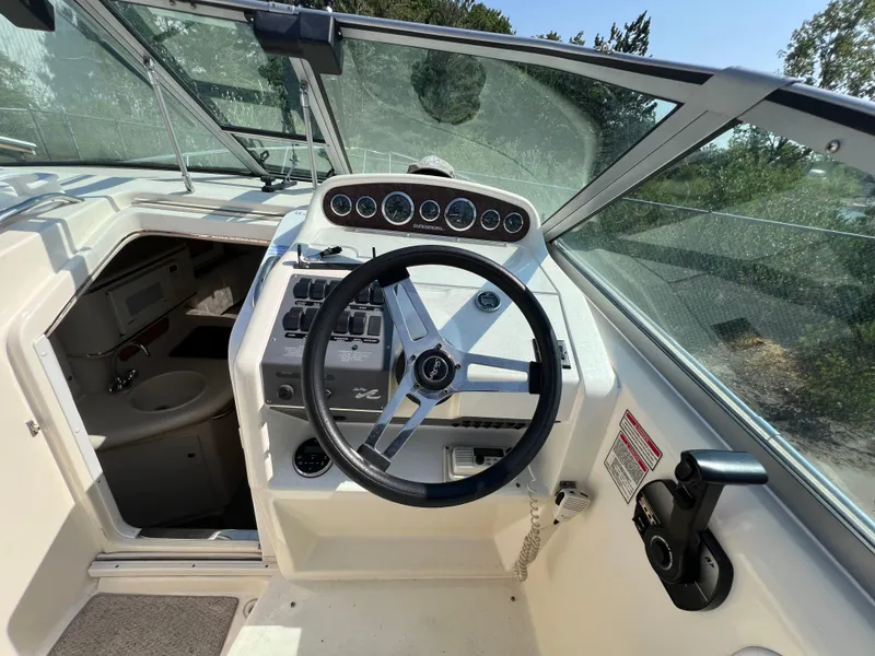 Slide: The Image of 1997 Sea Ray 270 Sundancer boat interior with white seating and control panel. - 9