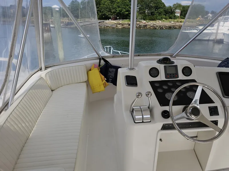 Slide: The Image of 1997 Ocean Yachts 45 Super Sport helm with steering wheel and seating, docked by the water. - 2