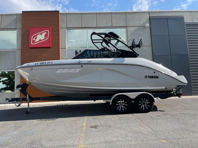 The Image of 2023 Yamaha Boats 222XD on trailer, parked outside dealership, clear sky background. - 1
