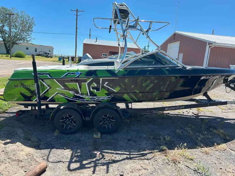 Slide: The Image of 2002 MasterCraft XStar boat with green and black design on a trailer. - 3