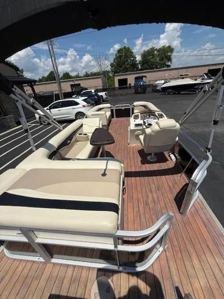 Slide: The Image of 2014 Bennington 22 SLX pontoon boat with spacious seating and wooden deck in a parking lot. - 5