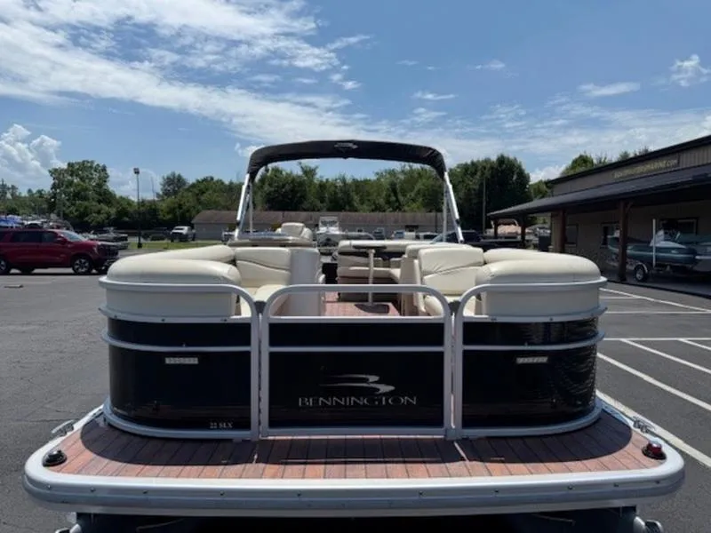 Slide: The Image of 2014 Bennington 22 SLX pontoon boat with beige seating, parked outdoors under a clear sky. - 6