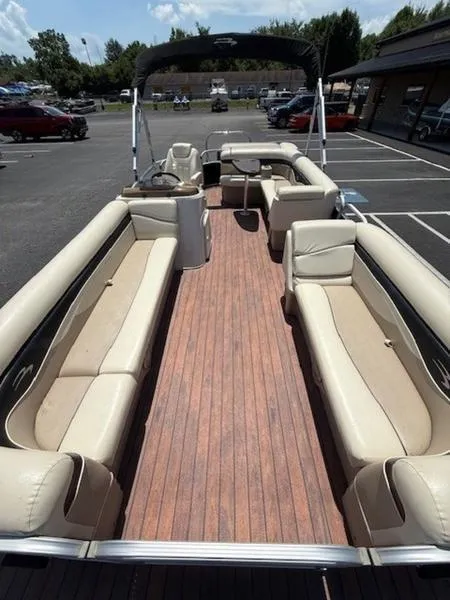 Slide: The Image of 2014 Bennington 22 SLX pontoon boat with spacious seating and wood-style flooring in a parking lot. - 7