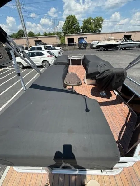 Slide: The Image of 2014 Bennington 22 SLX pontoon boat with covered seating, parked in a lot under a clear sky. - 9
