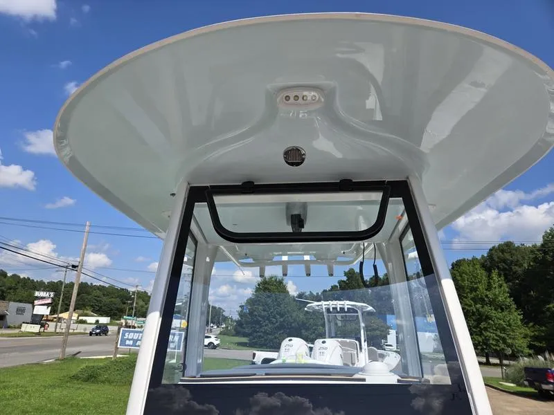 Slide: The Image of 2026 Sea Hunt Ultra 255se boat with T-top, parked outdoors under blue sky. - 6