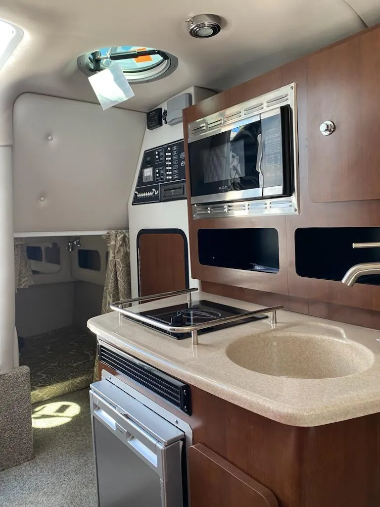 Slide: The Image of 2021 Crownline 264 CR boat interior with kitchenette, microwave, and sink. - 11