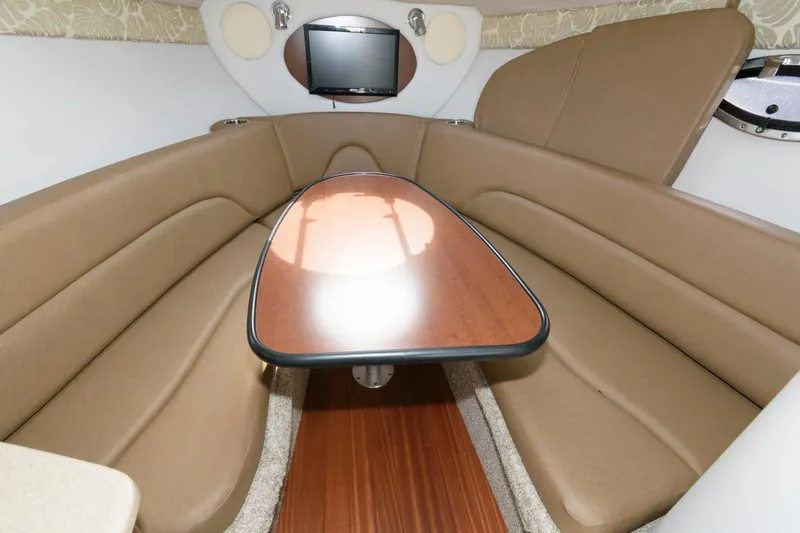 Slide: The Image of 2021 Crownline 264 CR cabin interior with brown seating and wooden table. - 14