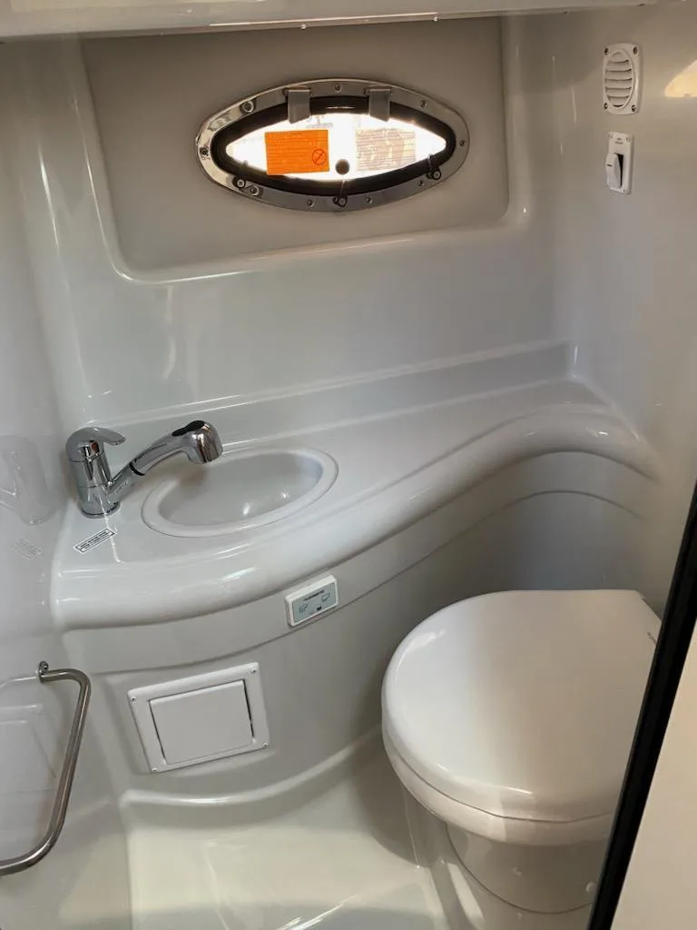 Slide: The Image of 2021 Crownline 264 CR boat bathroom with sink, toilet, and porthole window. - 18