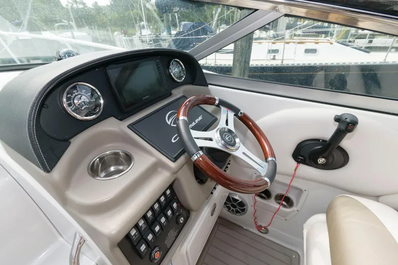 Slide: The Image of 2021 Crownline 264 CR boat dashboard with wood-accented steering wheel and control panel. - 6