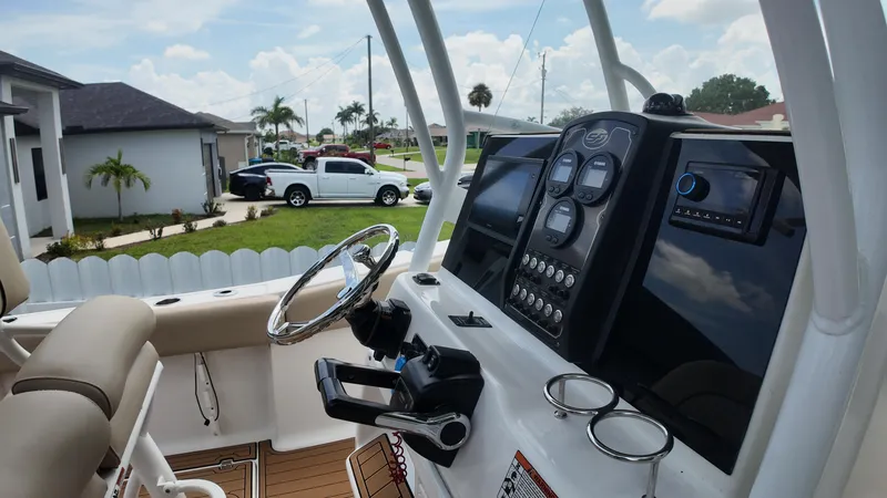 Slide: The Image of 2017 Sea Fox 266 Commander boat dashboard with steering wheel and controls, parked in a residential area. - 13
