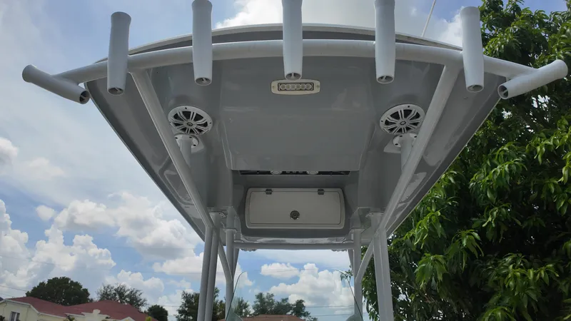 Slide: The Image of 2017 Sea Fox 266 Commander boat T-top with rod holders and speakers, under a cloudy sky. - 28