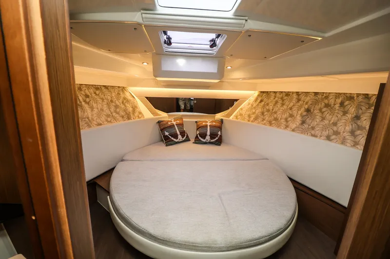 Slide: The Image of Cozy cabin interior of 2021 Jeanneau NC 1095 with round bed and decorative pillows. - 30