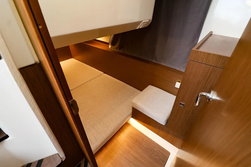 Slide: The Image of 2021 Jeanneau NC 1095 cabin interior with wooden finish and cozy bedding. - 35
