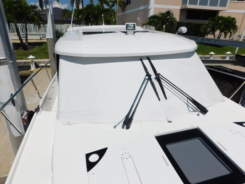 Slide: The Image of 2021 Jeanneau NC 1095 boat with covered windshield and wipers, docked near palm trees. - 38
