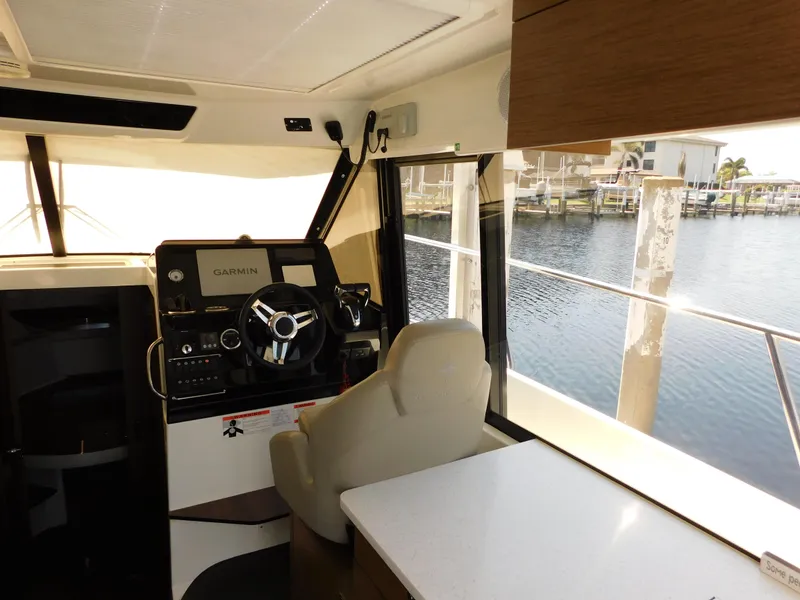 Slide: The Image of Interior of 2021 Jeanneau NC 1095 boat with helm, Garmin system, and waterfront view. - 13