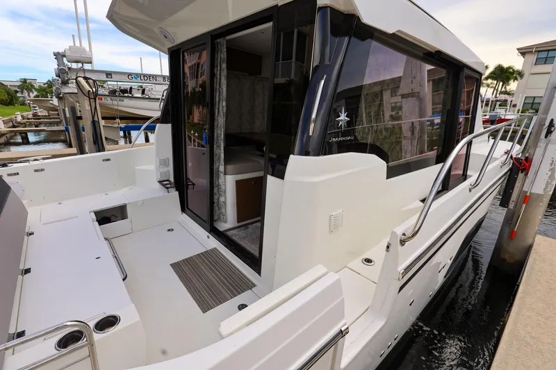 Slide: The Image of 2021 Jeanneau NC 1095 boat docked, showcasing spacious deck and modern design. - 7