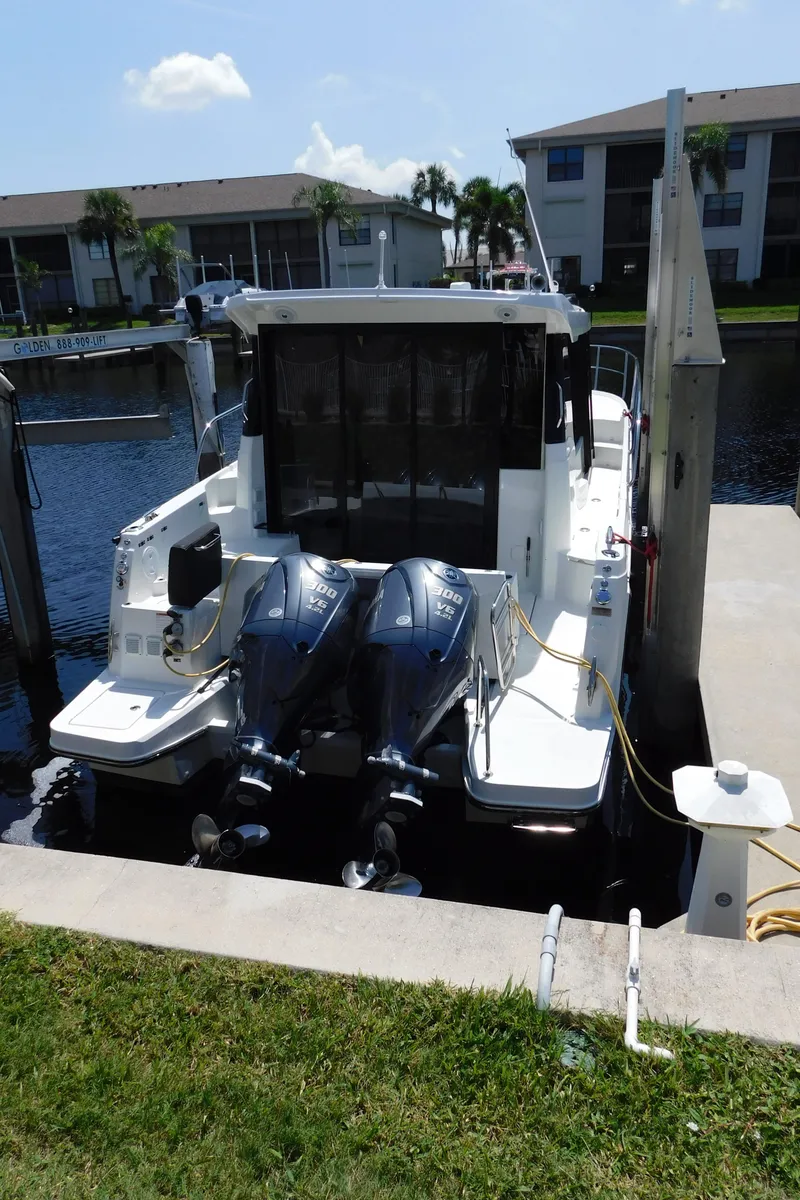 Slide: The Image of 2021 Jeanneau NC 1095 boat docked with dual outboard engines, residential backdrop. - 9
