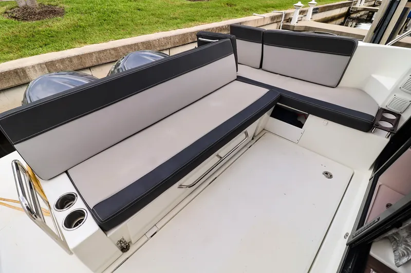 Slide: The Image of 2021 Jeanneau NC 1095 boat seating area with cushioned benches and cup holders. - 13