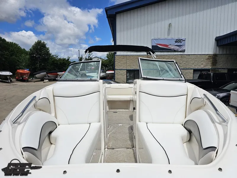 Slide: The Image of 2007 Rinker 246 Captiva Bowrider with white seating, parked outdoors under a blue sky. - 12
