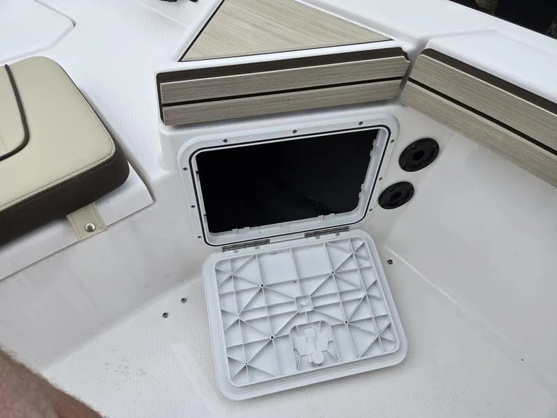 Slide: The Image of 2022 Yamaha Boats 195 FSH® SPORT storage compartment with open hatch and seating area. - 16