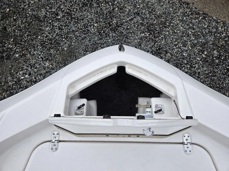 Slide: The Image of 2022 Yamaha Boats 195 FSH® SPORT bow storage compartment, open on gravel surface. - 20