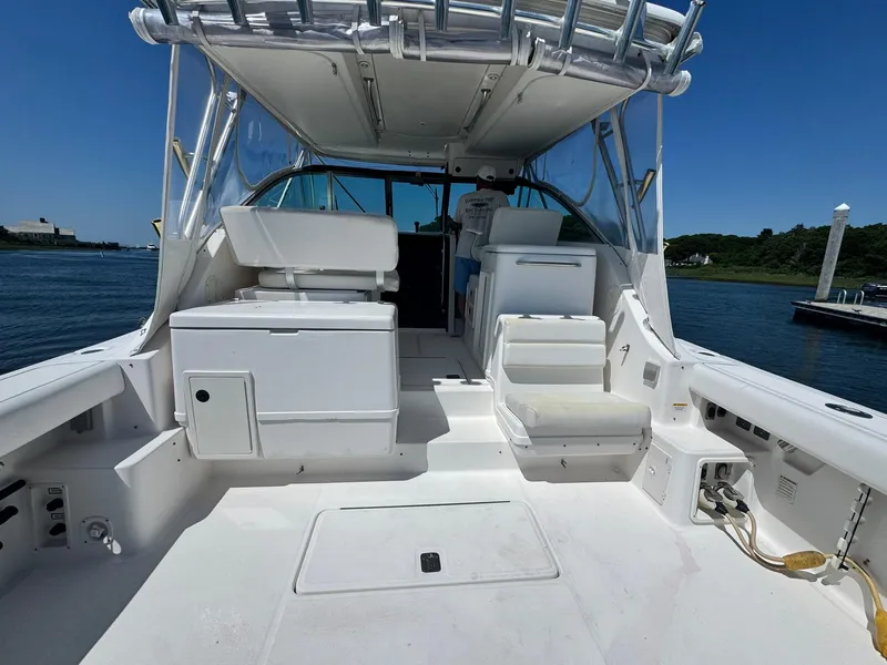 Slide: The Image of 2003 Pursuit 3400 Express boat interior, featuring seating and storage, docked by the water. - 10
