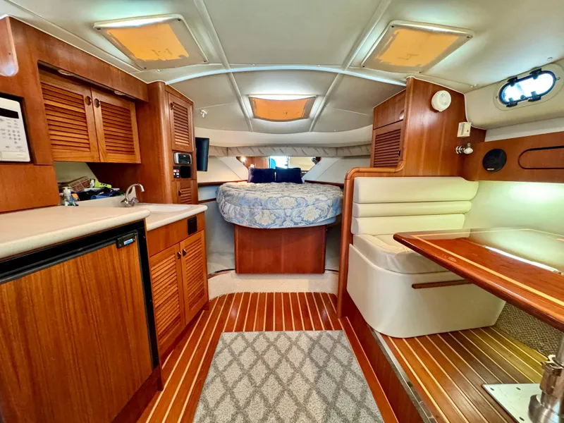 Slide: The Image of Interior of 2003 Pursuit 3400 Express yacht with wood finishes and cozy seating area. - 17