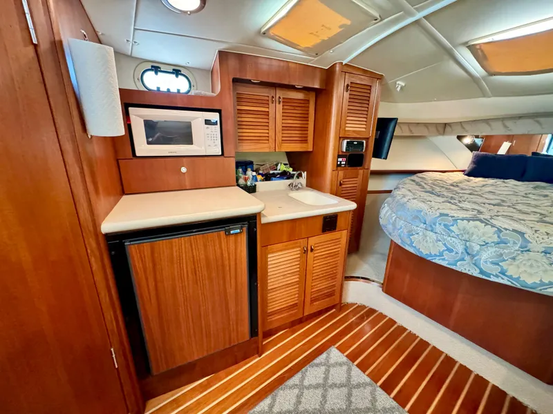 Slide: The Image of 2003 Pursuit 3400 Express cabin with kitchenette, microwave, mini-fridge, and bed. - 18