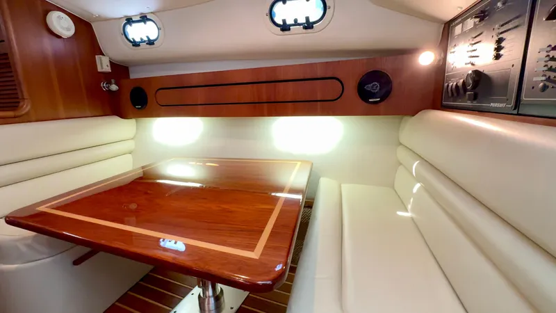 Slide: The Image of 2003 Pursuit 3400 Express cabin interior with wood table and white seating. - 23