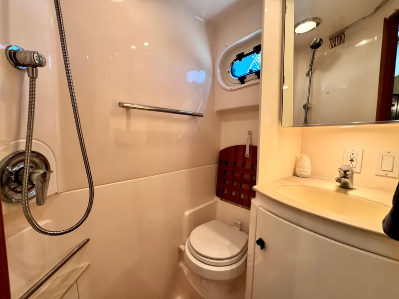 Slide: The Image of 2003 Pursuit 3400 Express boat bathroom with shower, sink, and porthole window. - 24