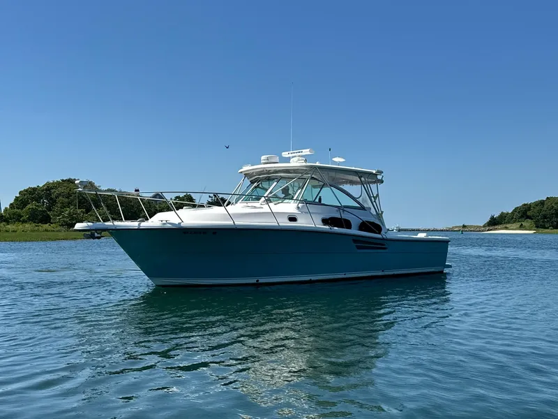 Slide: The Image of 2003 Pursuit 3400 Express boat on calm water under clear blue sky. - 3