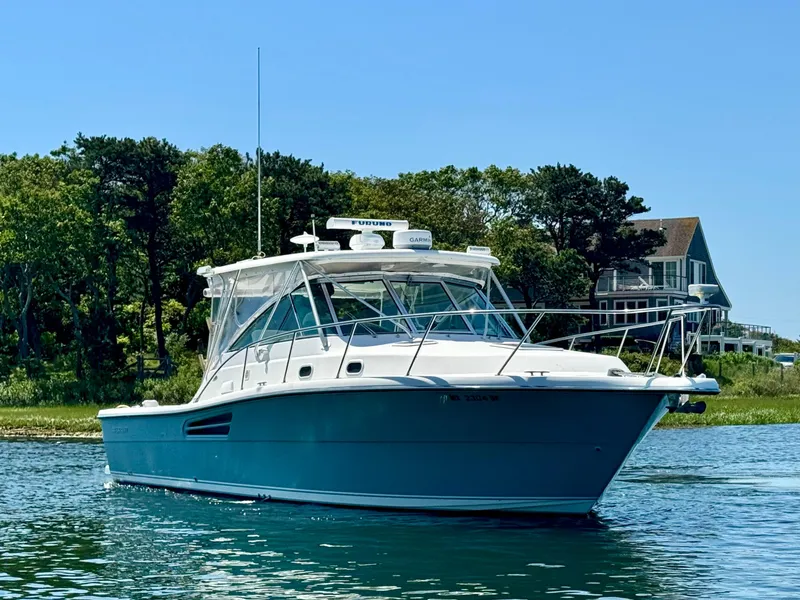 Slide: The Image of 2003 Pursuit 3400 Express boat on water, surrounded by trees and a house in the background. - 7