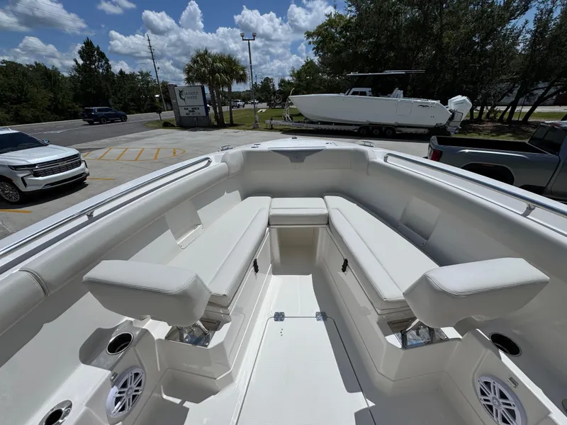 Slide: The Image of 2026 Sailfish 272 CC boat interior with white seating and cup holders, parked outdoors. - 23