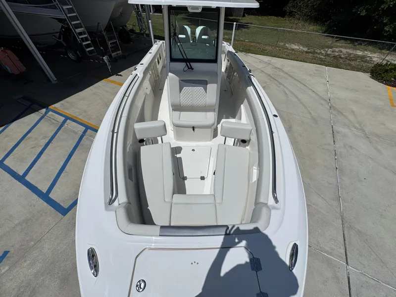 Slide: The Image of 2026 Sailfish 272 CC boat interior with seating and console, parked on concrete. - 25