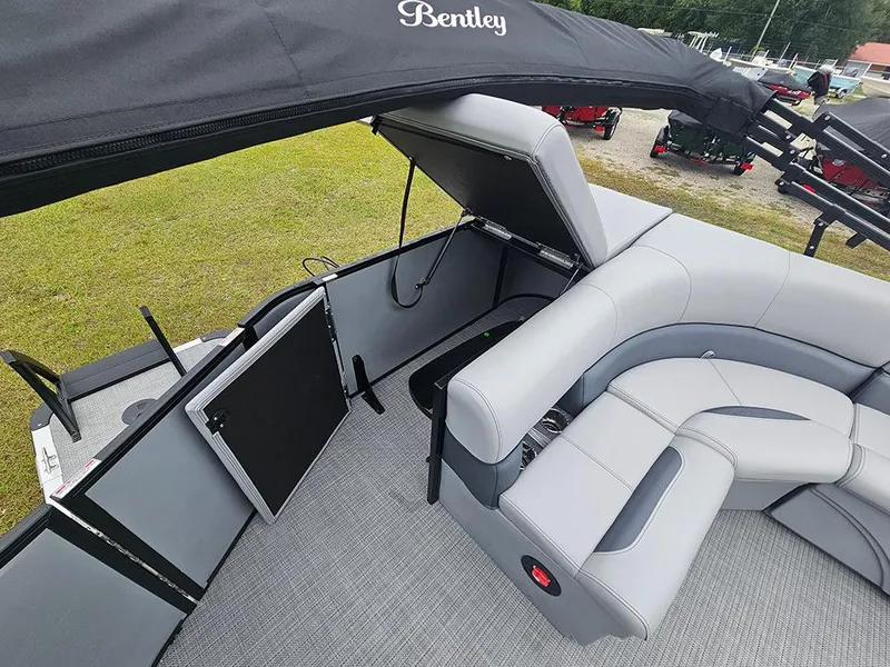 Slide: The Image of 2026 Bentley Pontoons Legacy 243 Cruise interior with gray seating and helm, parked outdoors. - 12