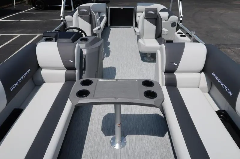 Slide: The Image of 2026 Bennington S Quad Bench 22 SSR interior with gray and white seating, cup holders, and steering console. - 13
