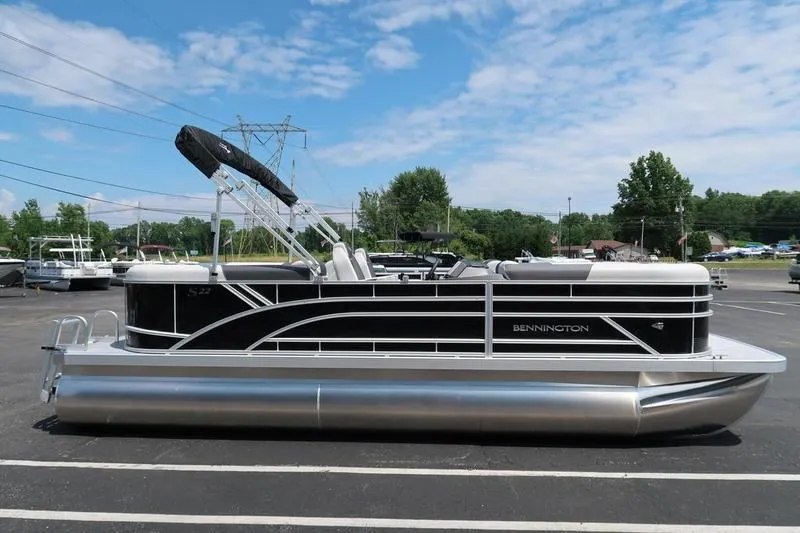 Slide: The Image of 2026 Bennington S Quad Bench 22 SSR pontoon boat in a parking lot under blue skies. - 8