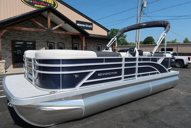 Slide: The Image of 2026 Bennington S Quad Bench 22 SSR pontoon boat parked outside a dealership. - 5