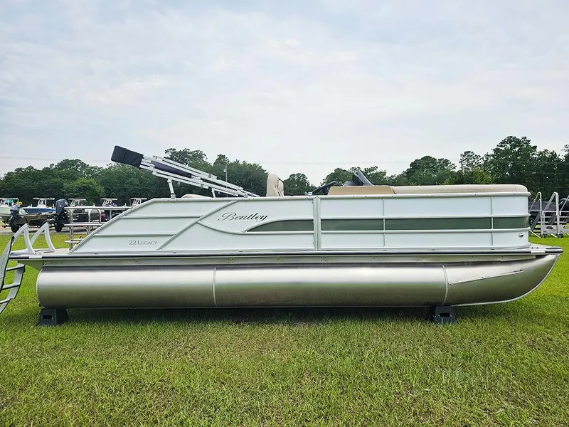 Slide: The Image of 2026 Bentley Pontoons 223 Legacy Swingback with cover, parked outdoors on a sunny day. - 1