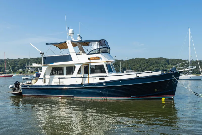 The Image of 2002 Grand Banks 46 Europa yacht on calm water, with clear blue sky background. - 0