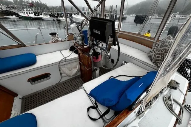 Slide: The Image of Cockpit of 1990 Bristol 47.7 Cutter/Sloop with blue cushions and steering wheel, docked in marina. - 33