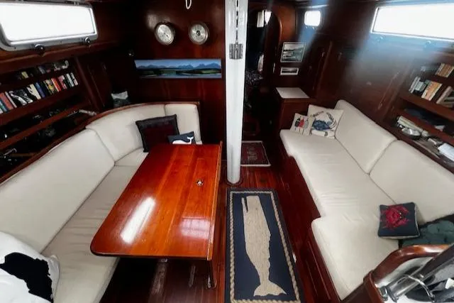 Slide: The Image of Interior of 1990 Bristol 47.7 Cutter/Sloop with wooden table, white seating, and nautical decor. - 5