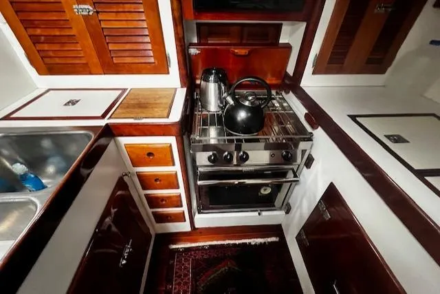 Slide: The Image of 1990 Bristol 47.7 Cutter/Sloop galley with stove, sink, and wooden cabinetry. - 9