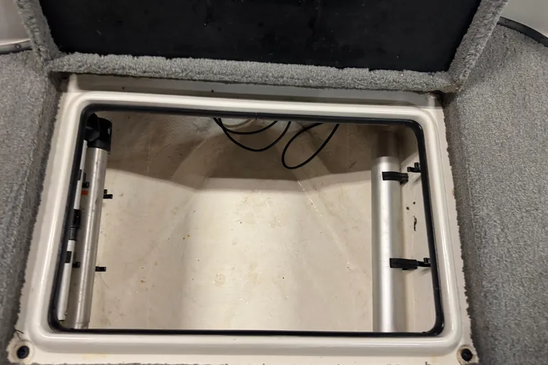 Slide: The Image of Open storage compartment in 2011 Nitro 290 Sport boat, featuring carpeted edges and metal supports. - 19