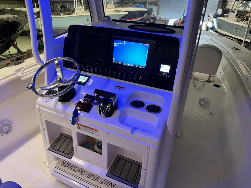 Slide: The Image of 2021 Sea Hunt Gamefish 27 boat dashboard with steering wheel and electronic controls. - 11