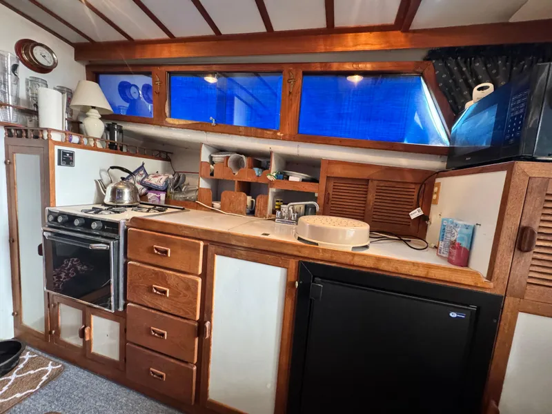 Slide: The Image of 1983 Rough Water Flybridge kitchen with stove, cabinets, and appliances. Cozy nautical interior. - 11