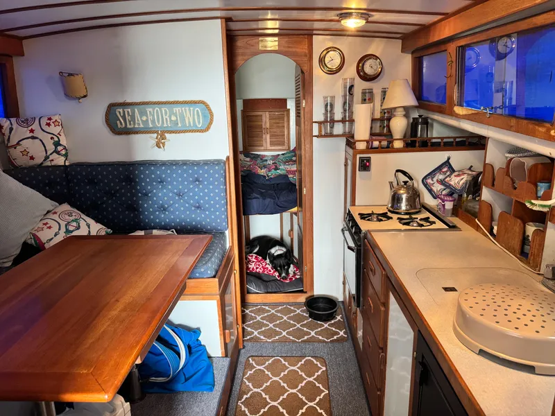 Slide: The Image of Cozy 1983 Rough Water Flybridge interior with kitchen, seating, and nautical decor. - 13