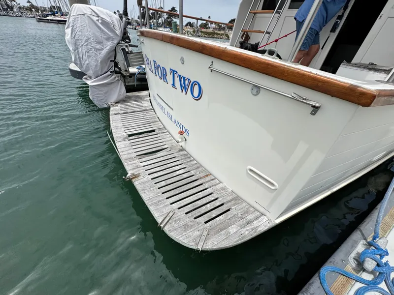Slide: The Image of 1983 Rough Water Flybridge boat docked, featuring wooden deck and covered motor. - 4