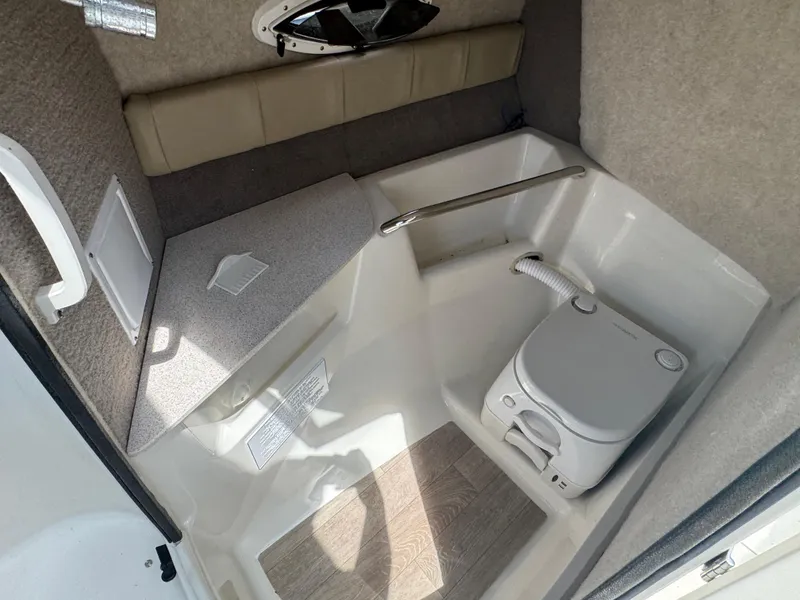 Slide: The Image of 2018 Stingray 234 LR boat interior with compact toilet and seating area. - 14
